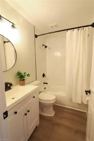 Full bathroom featuring vanity, hardwood / wood-style floors, toilet, and shower / bath combination with curtain