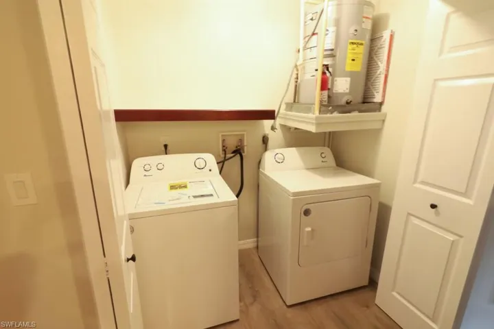 Clothes washing area with water heater, washing machine and dryer, and light wood-type flooring