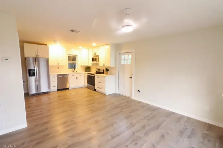 Kitchen featuring sink, appliances with stainless steel finishes, light wood-type flooring, and white cabinets