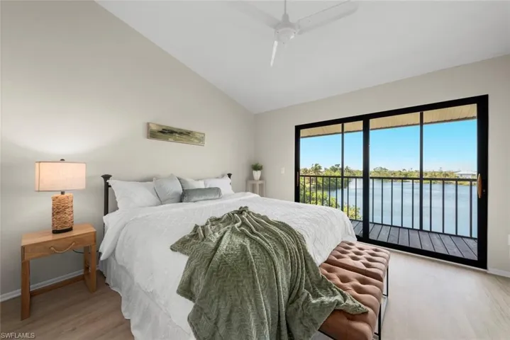 Bedroom featuring a water view, baseboards, access to outside, ceiling fan, and wood finished floors