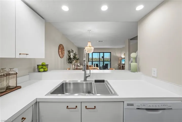 Kitchen featuring light countertops, a sink, white dishwasher, white cabinets, and recessed lighting