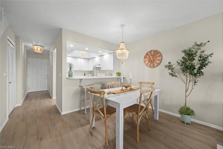 Dining room with baseboards, light wood-style flooring, an inviting chandelier, and recessed lighting