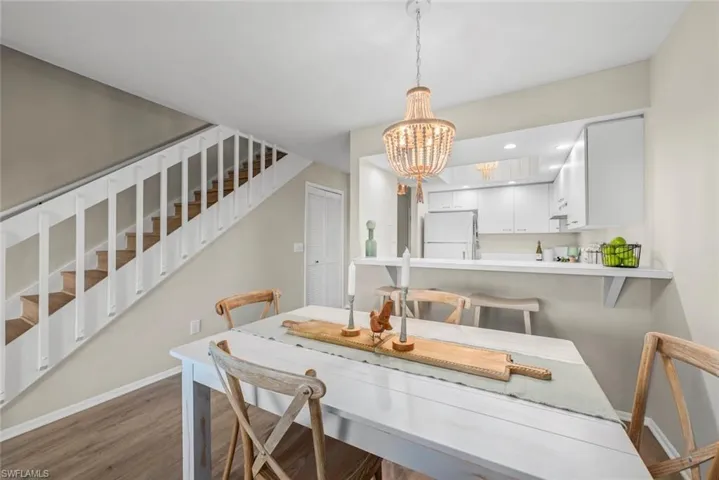 Dining space featuring stairway, baseboards, a chandelier, and wood finished floors