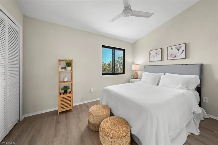 Bedroom featuring a closet, baseboards, ceiling fan, wood finished floors, and lofted ceiling
