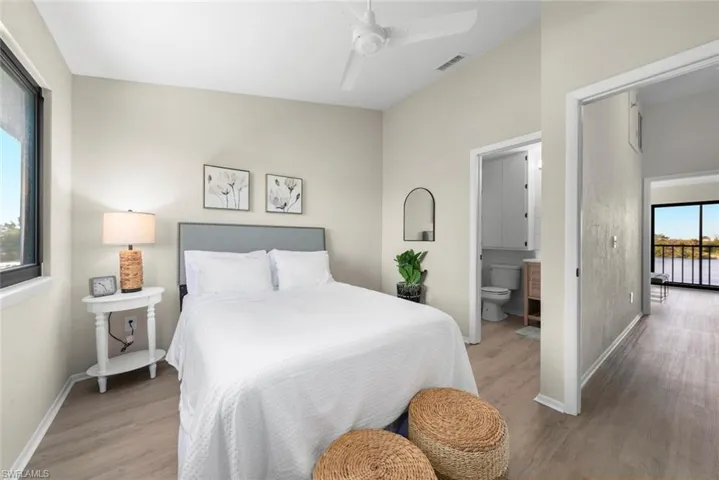 Bedroom with connected bathroom, light wood-style flooring, baseboards, visible vents, and ceiling fan