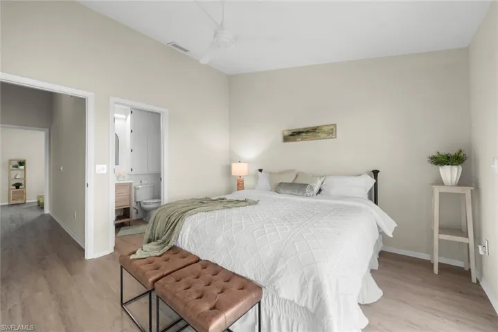 Bedroom with baseboards, visible vents, light wood-style flooring, and ensuite bathroom