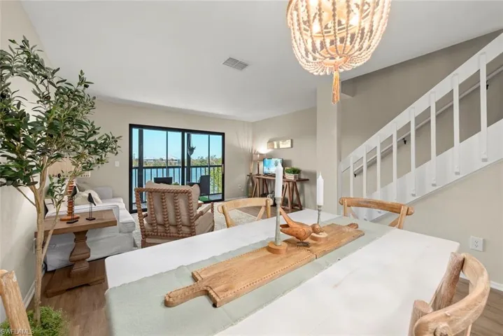 Dining space with stairs, baseboards, a chandelier, visible vents, and wood finished floors