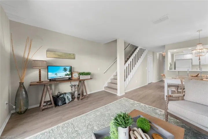 Living room with visible vents, baseboards, stairs, and wood finished floors