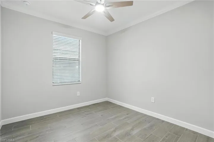 Unfurnished room with a ceiling fan, crown molding, light wood-style floors, and a smoke detector