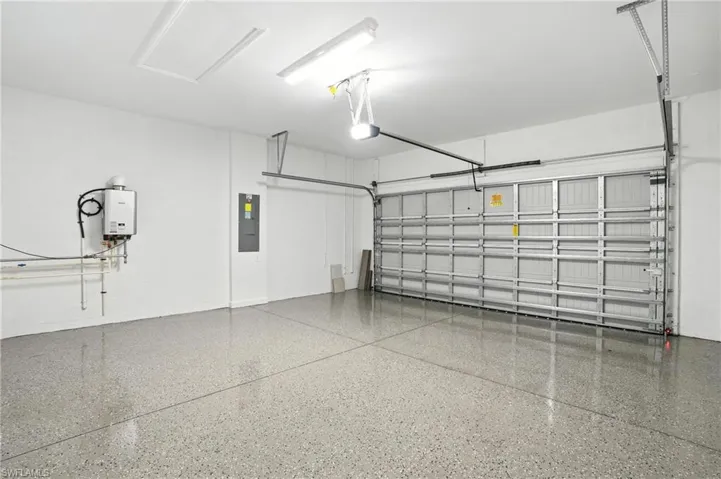 Garage featuring electric panel, a garage door opener, and water heater