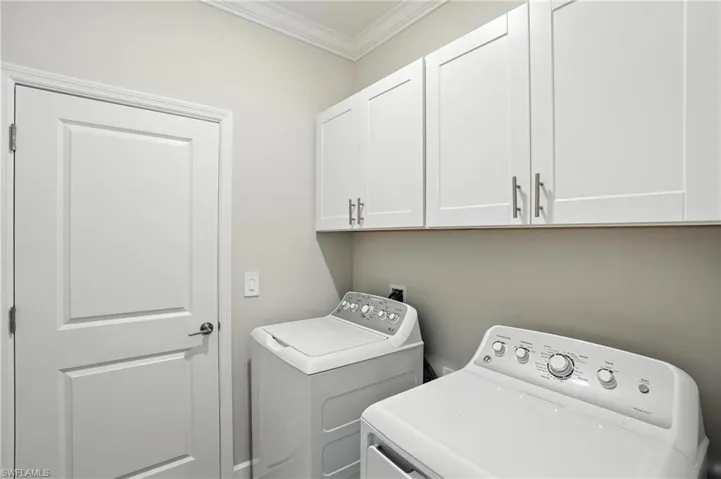 Washroom with cabinet space, washing machine and clothes dryer, and ornamental molding