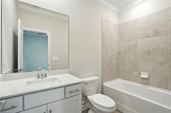 Bathroom with crown molding, vanity, and bathing tub / shower combination