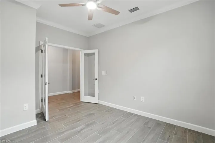 Spare room with a ceiling fan, french doors, light wood finished floors, and ornamental molding