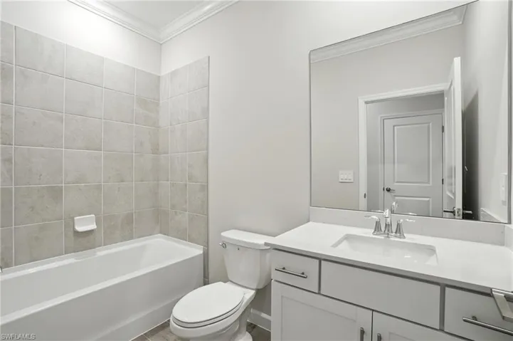 Bathroom featuring ornamental molding, vanity, and bathtub / shower combination