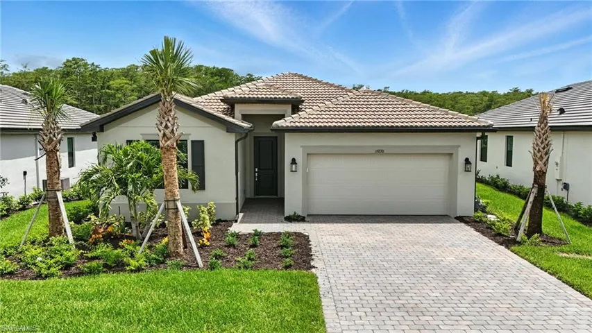 Single story home with an attached garage, stucco siding, decorative driveway, and a tiled roof