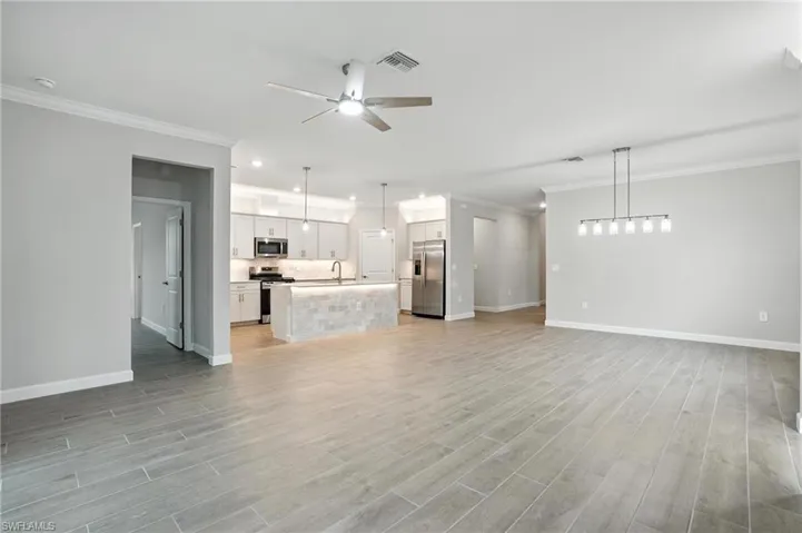 Unfurnished living room with a ceiling fan, light wood-style flooring, crown molding, and recessed lighting