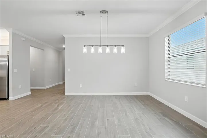 Unfurnished dining area with ornamental molding and light wood-style floors