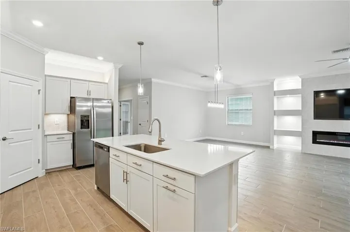 Kitchen featuring appliances with stainless steel finishes, light wood finished floors, crown molding, open floor plan, and light countertops