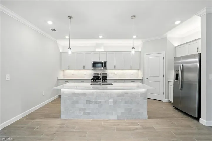 Kitchen featuring stainless steel appliances, crown molding, light countertops, decorative backsplash, and wood tiled floors