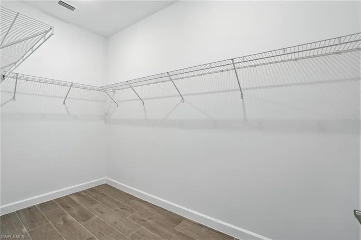 Walk in closet with dark wood-style floors