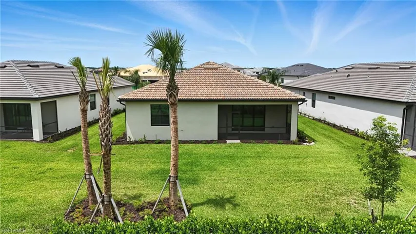 Back of house featuring a lawn, a sunroom, stucco siding, and a tile roof