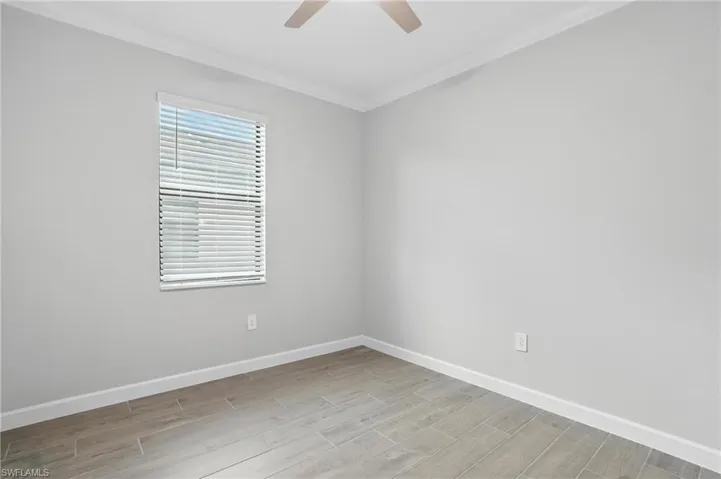 Unfurnished room featuring crown molding, a ceiling fan, and light wood-style floors