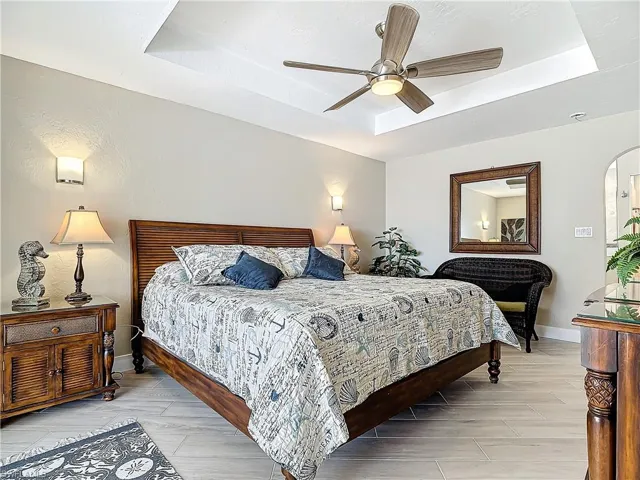 Bedroom with access to exterior, a raised ceiling, and ceiling fan