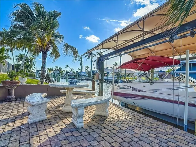 View of lower patio featuring a water view and a dock