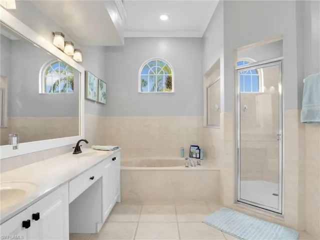 Primary Bathroom with Dual Sinks, Soaking Tub, Walk-In Shower with Glass Enclosure, Framed Vanity Mirror, and Crown Molding