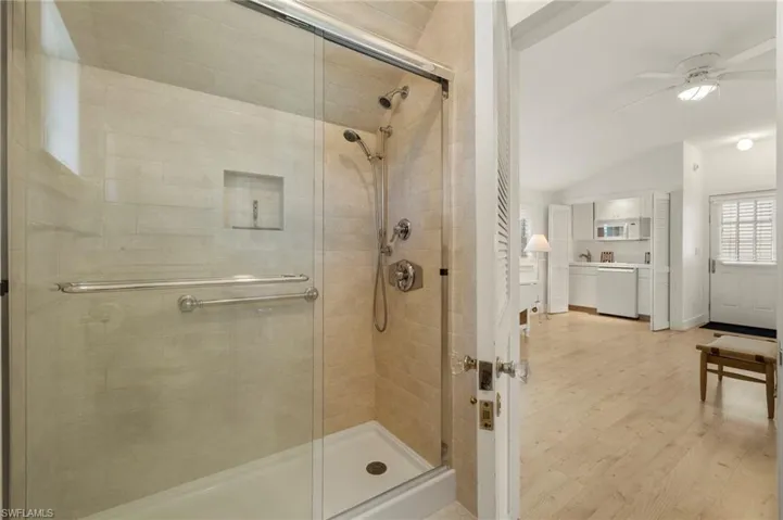 Guest Suite bathroom featuring vaulted ceiling, light wood-style flooring, a stall shower, and a ceiling fan