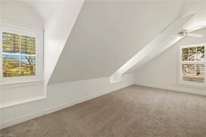 Upstairs second bedroom with vaulted ceiling, carpet, and ceiling fan