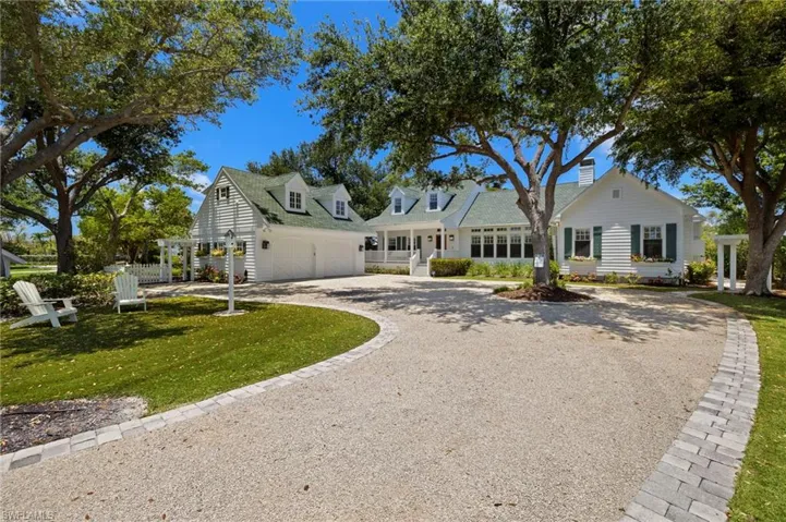 Cape cod house featuring driveway, a front lawn, a garage, and a chimney