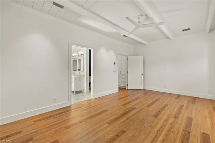 Primary bedroom  with beam ceiling, light wood-style floors, and a ceiling fan