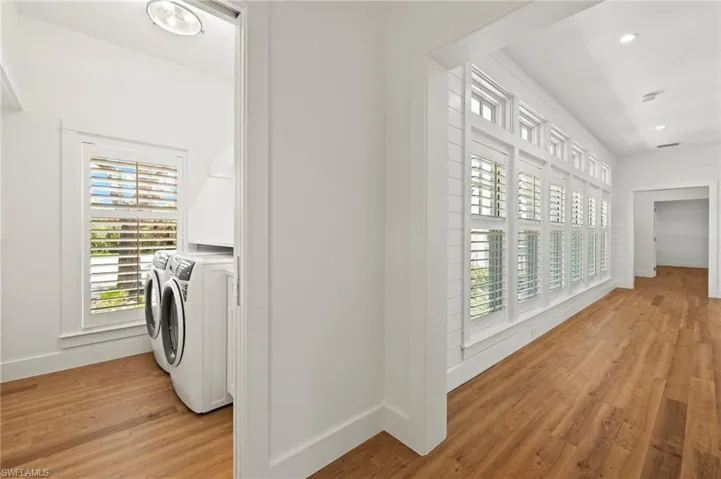 Hallway with light wood finished floors, separate washer and dryer, and recessed lighting