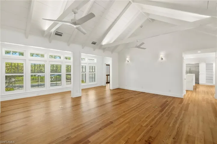 Unfurnished living room featuring beamed ceiling, light wood-style floors, high vaulted ceiling, and ceiling fan