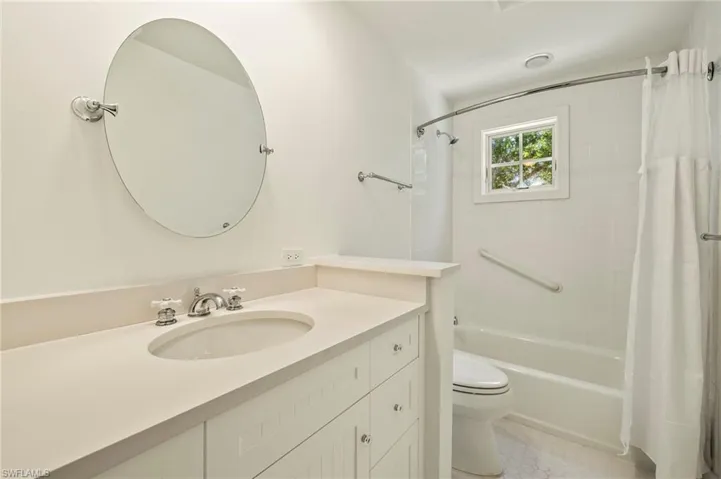 Guest bathroom with vanity and shower / bathtub combination with curtain