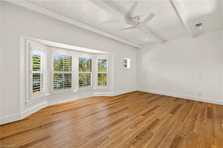 Primary bedroom  with beam ceiling, light wood finished floors, and a ceiling fan