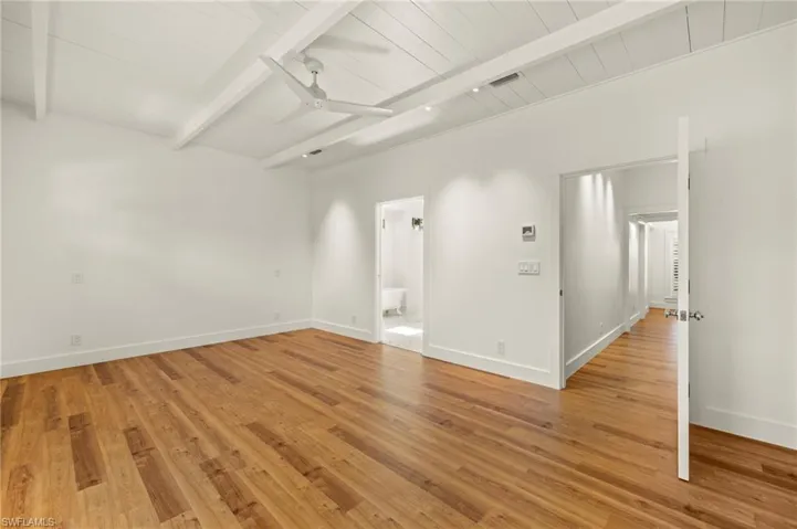 Primary bedroom featuring beamed ceiling, light wood-style floors, and a ceiling fan