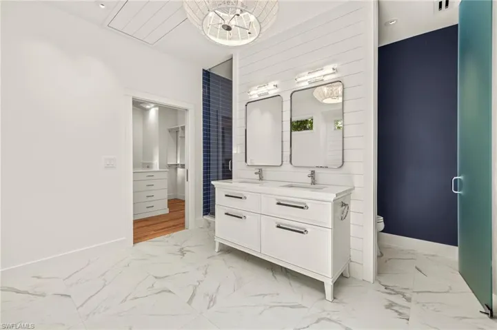 Primary bathroom with double vanity and light marble finish floors