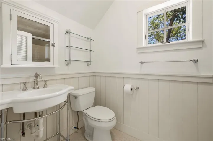 Guest Suite bathroom with lofted ceiling, a shower with shower door, and a wainscoted wall