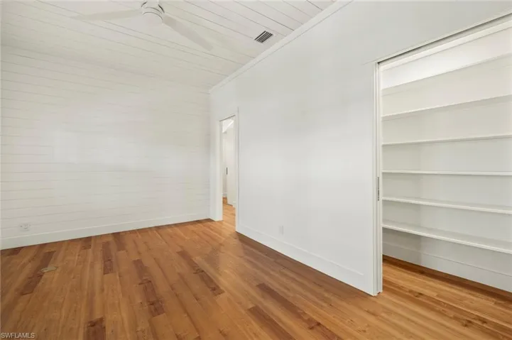 Den/Office with light wood-type flooring, ceiling fan, a walk in closet, wooden ceiling, and crown molding