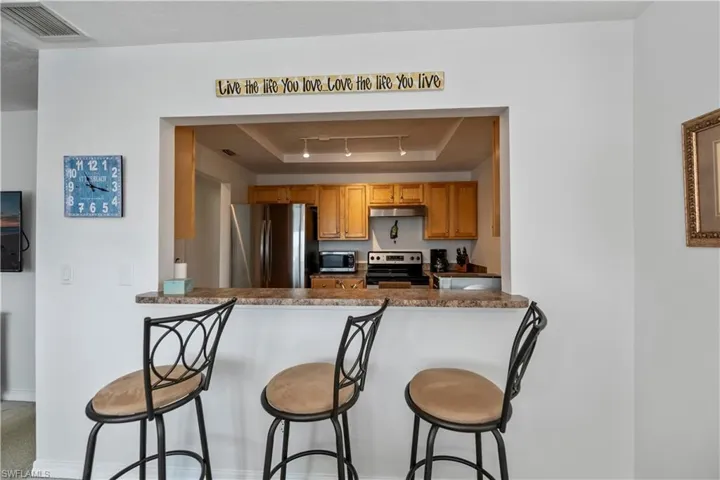 Kitchen featuring a breakfast bar, kitchen peninsula, a tray ceiling, and stainless steel appliances