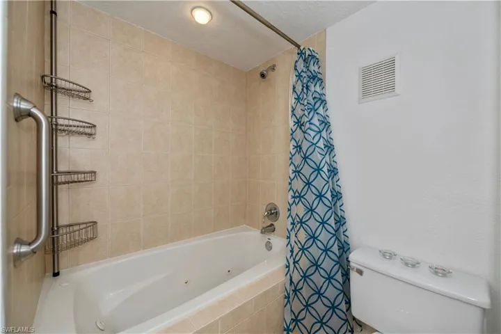 Bathroom featuring toilet, a textured ceiling, and shower / bathtub combination with curtain