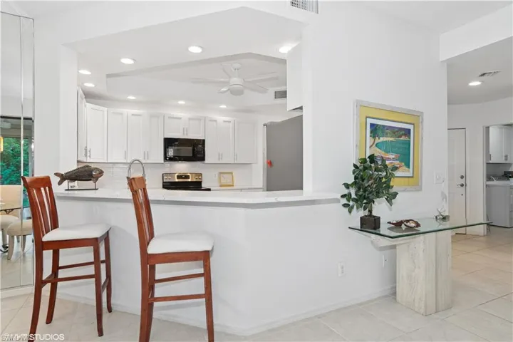 Kitchen with ceiling fan, stainless steel appliances, a peninsula, backsplash, and washer and clothes dryer