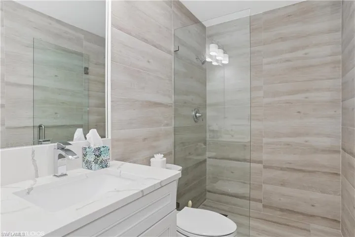 Bathroom with toilet, a tile shower, and vanity