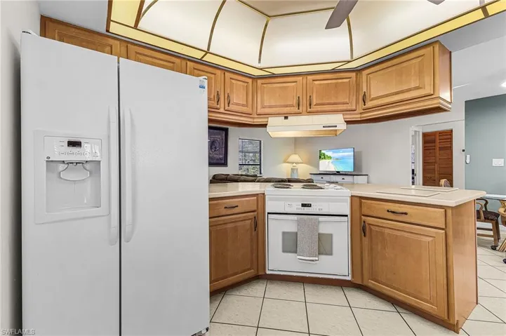 Kitchen featuring white appliances, brown cabinetry, light countertops, and ceiling fan