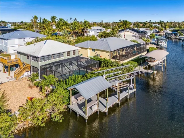 Dock area with boat lift, a water view, glass enclosure, and a residential view