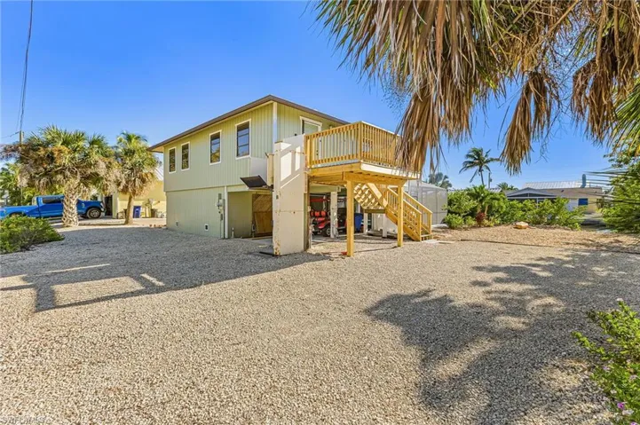 Front of house with stairway, a wooden deck, and a patio