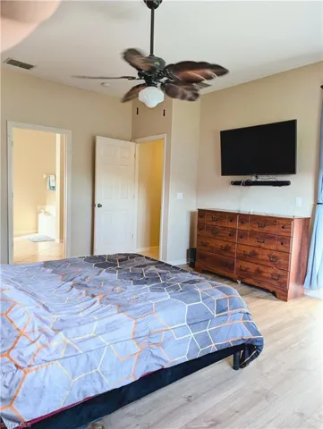 Bedroom featuring connected bathroom, hardwood / wood-style flooring, and ceiling fan