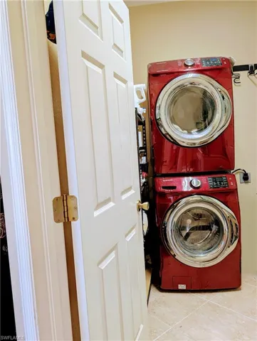 Washroom tiled floor featuring stacked washing machine and dryer.